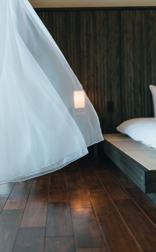 風が通り抜ける、白いカーテンが印象的なベッドルーム