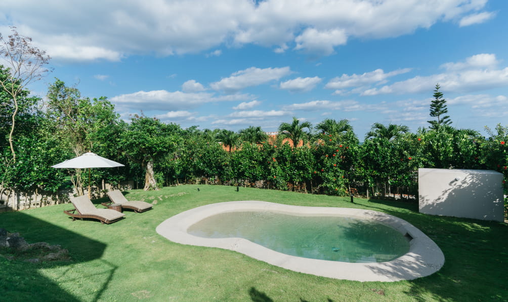 沖縄の緑に囲まれた、プライベートプールと芝生の庭