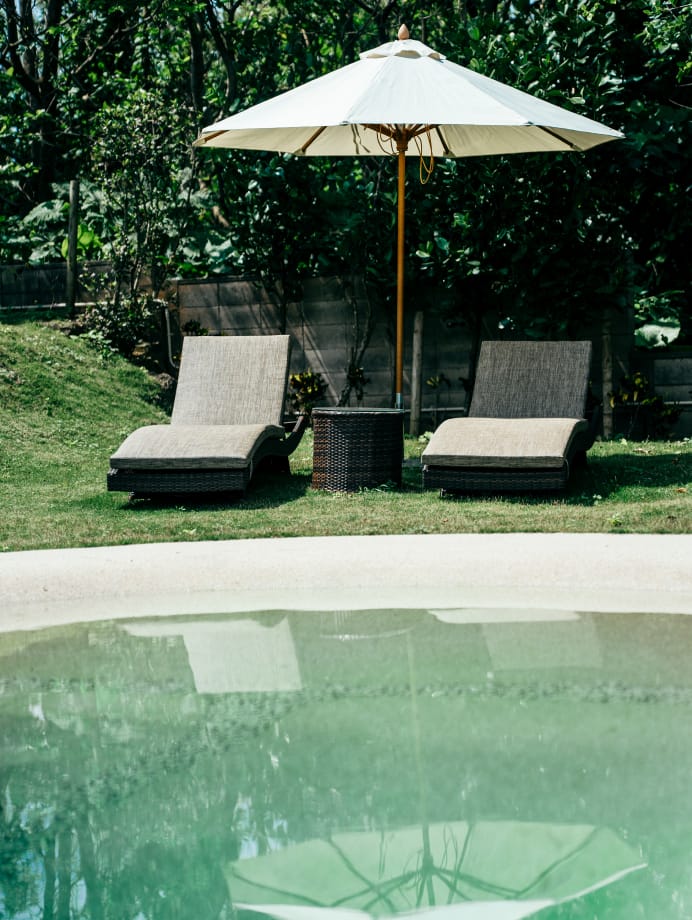 極海静邸の庭に設けられたリクライニングチェアとパラソル