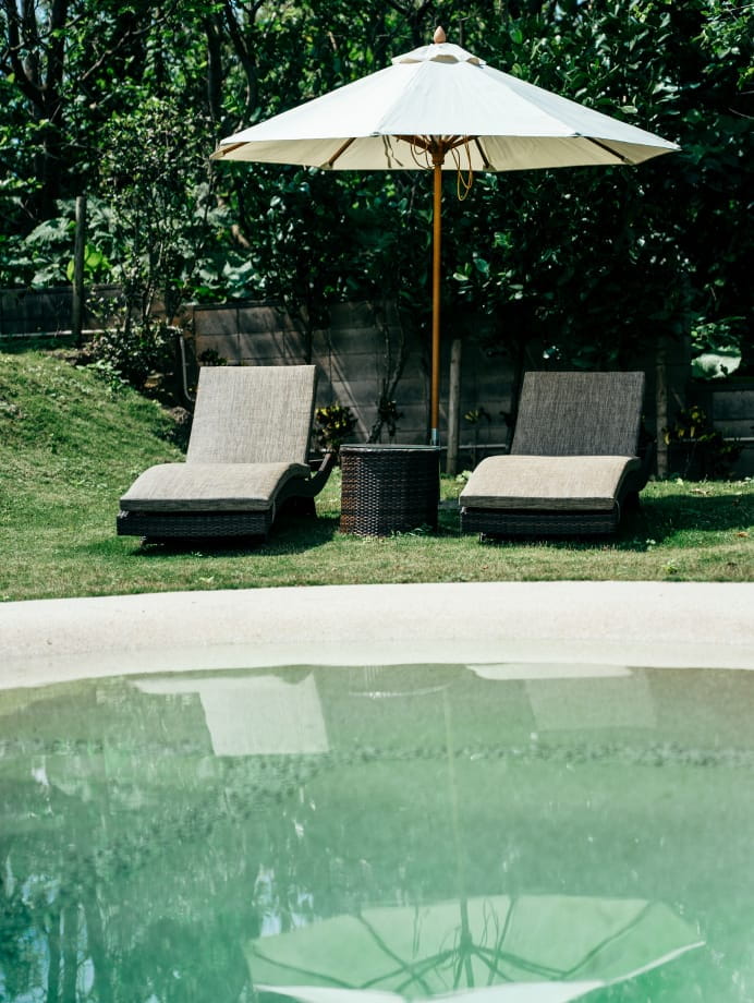 極海静邸の庭に設けられたリクライニングチェアとパラソル